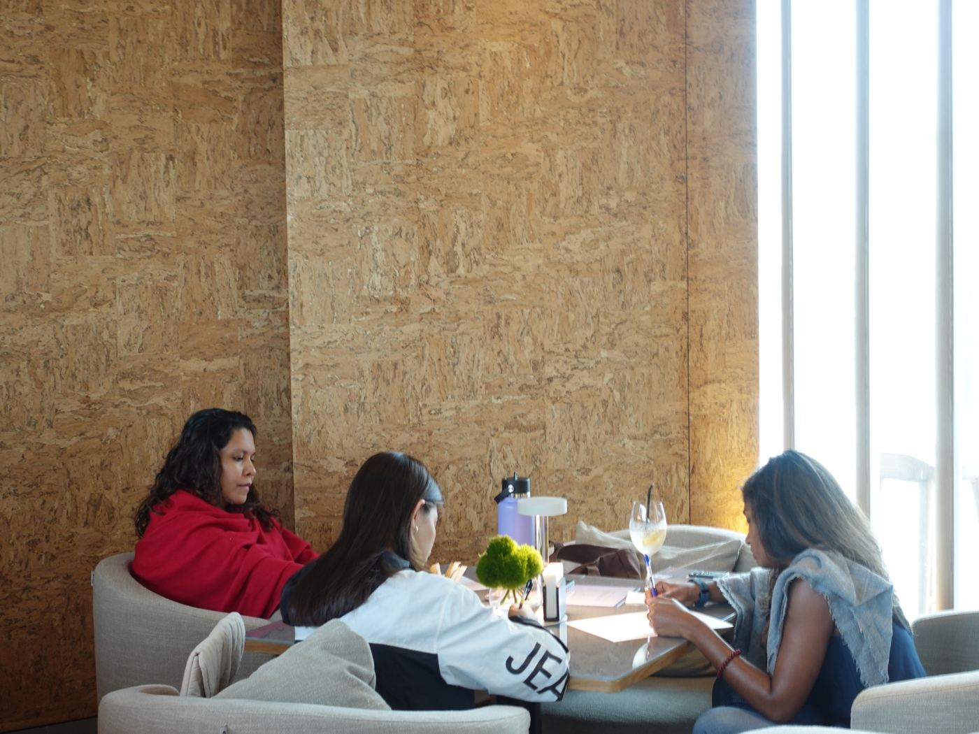 Three guests talk and write together on a low sofa