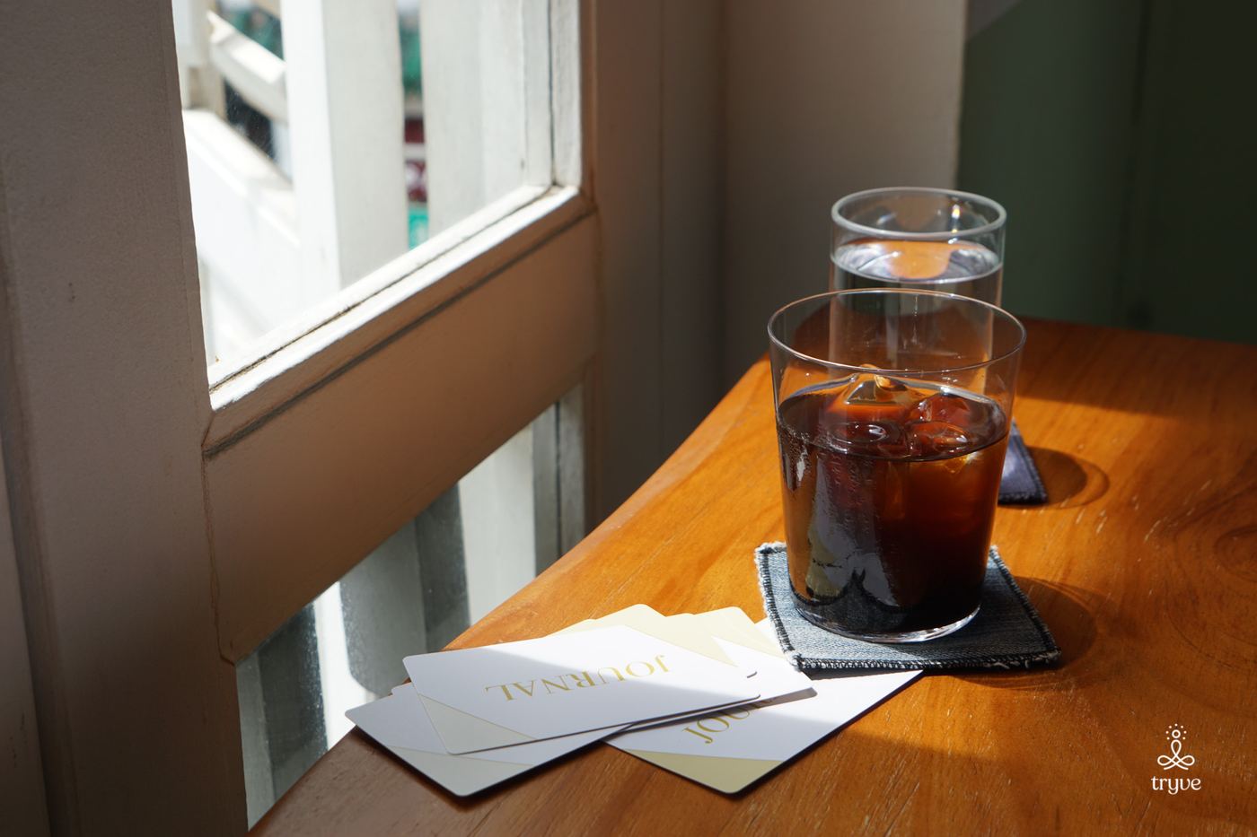 An iced coffee on a sunny windowsill beside printed prompt cards